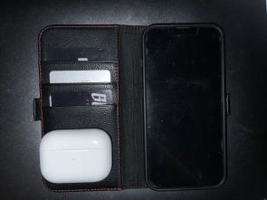 A picture showing an iPhone in fold out case with card inserts, and airpods
